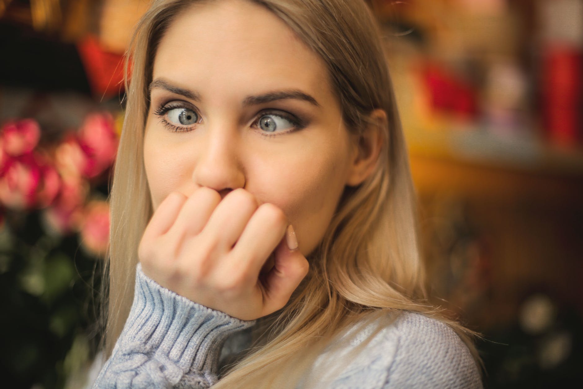 woman in gray sweater holding her face