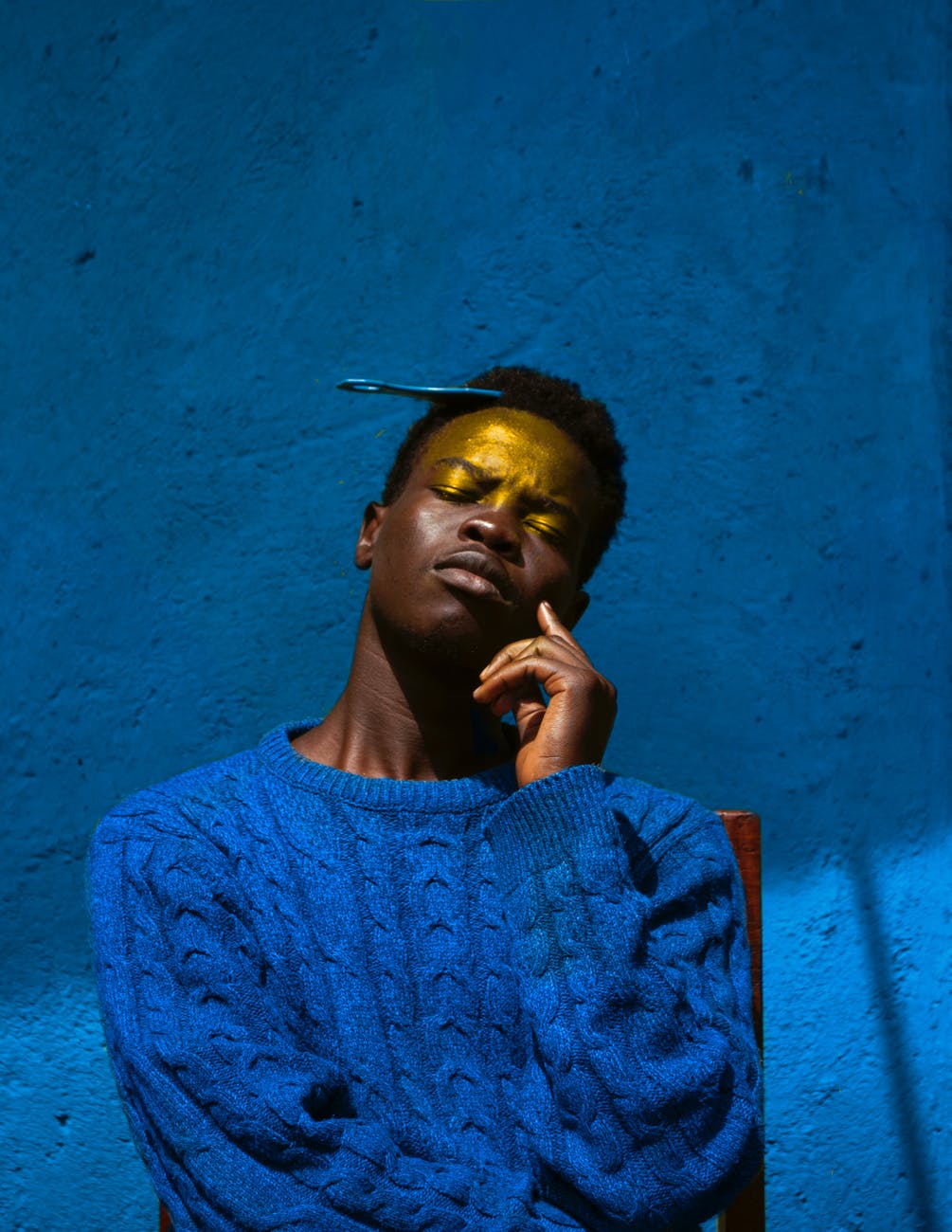 man in blue knit sweater against blue wall