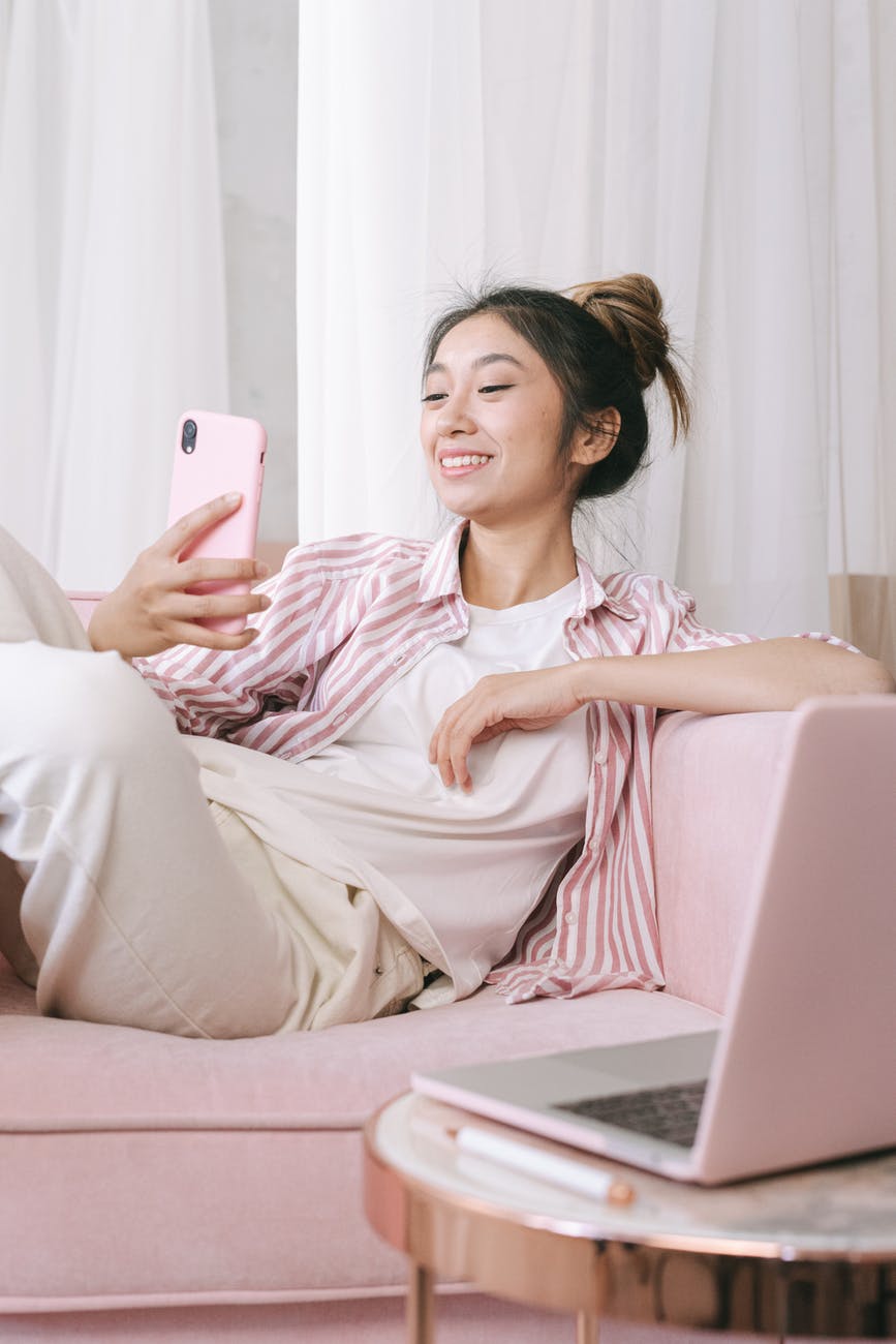 a woman sitting on the couch smiling while holding her phone