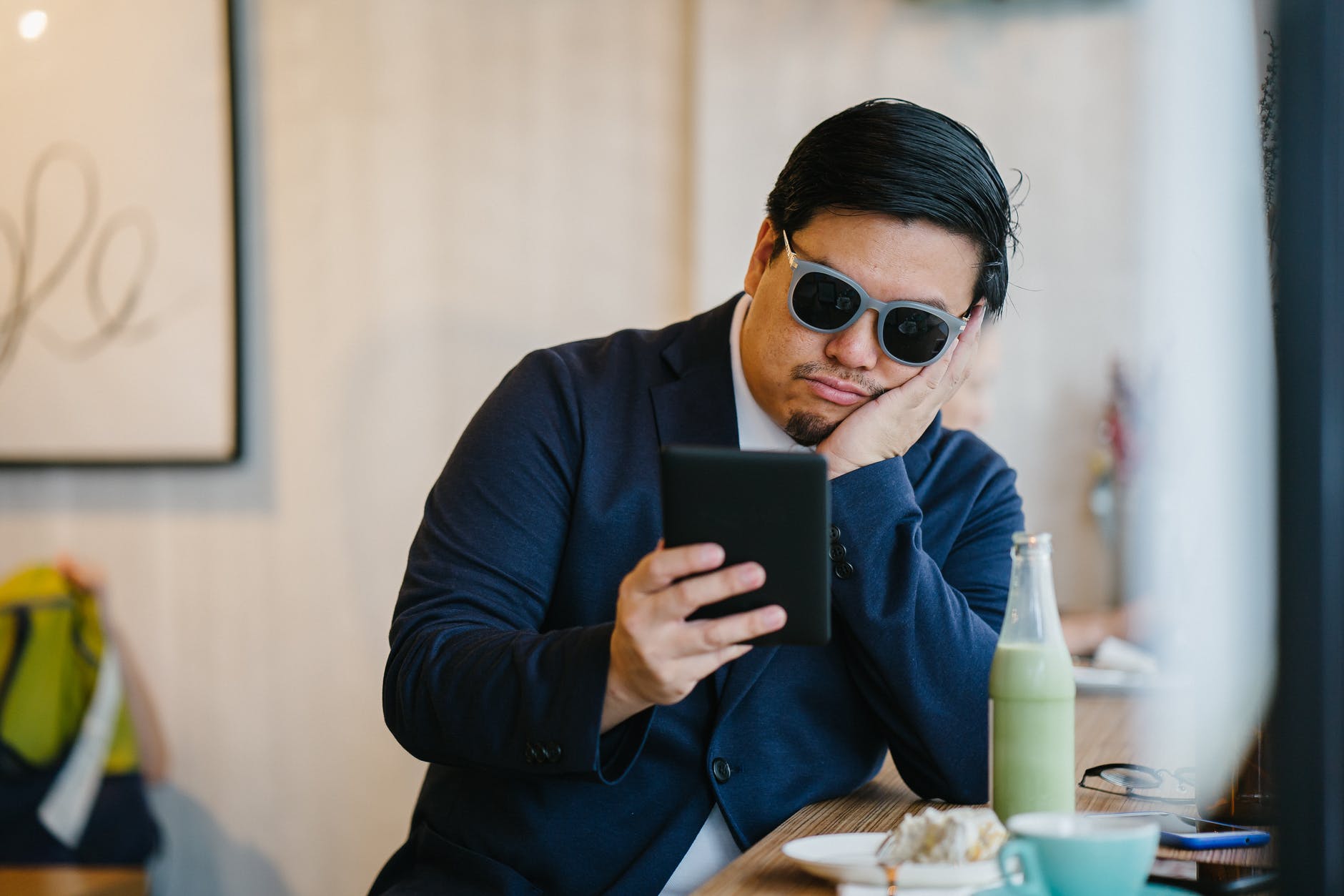 man wearing grey sunglasses holding black tablet